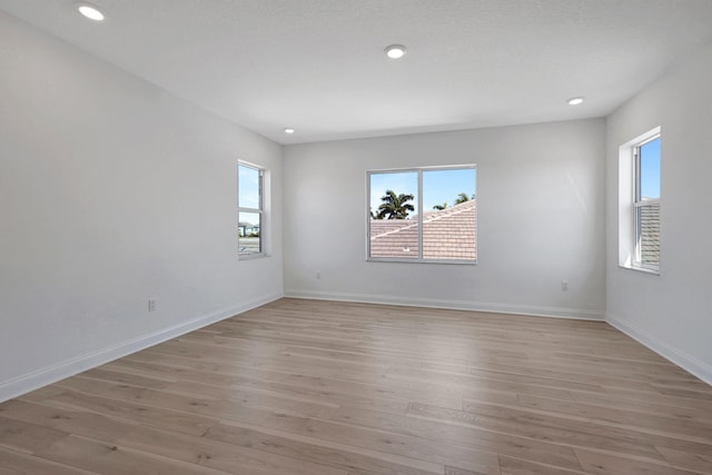 unfurnished room with light wood-type flooring, baseboards, and recessed lighting