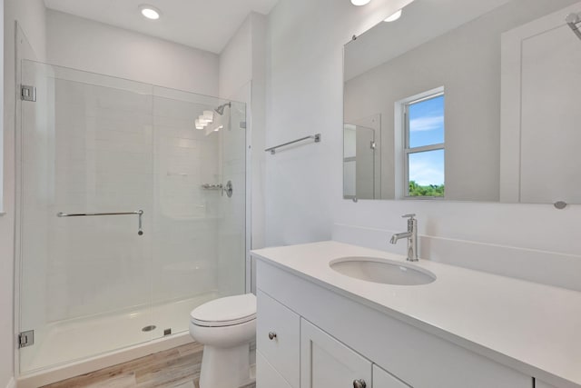 bathroom featuring toilet, a stall shower, wood finished floors, and vanity