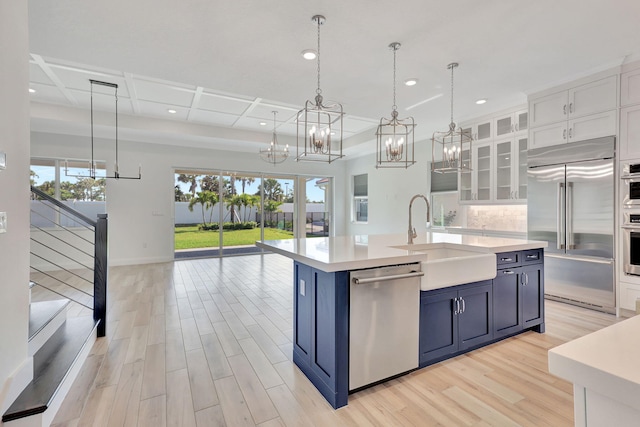 kitchen featuring glass insert cabinets, light countertops, stainless steel appliances, and white cabinetry