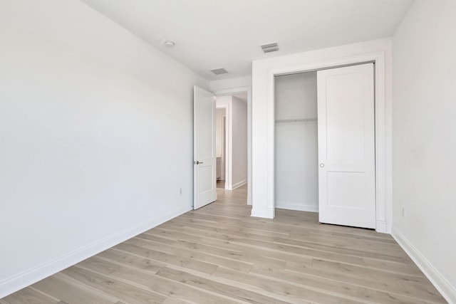 unfurnished bedroom featuring light wood-style floors, a closet, visible vents, and baseboards