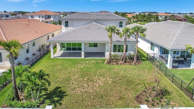 back of house featuring a residential view, a tile roof, a fenced backyard, and a lawn