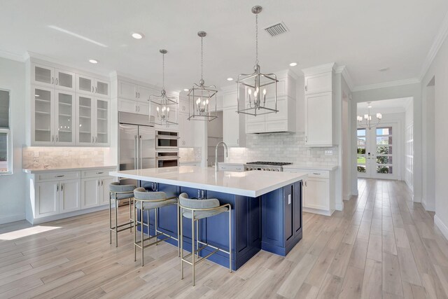 kitchen featuring stainless steel appliances, white cabinetry, visible vents, light countertops, and glass insert cabinets