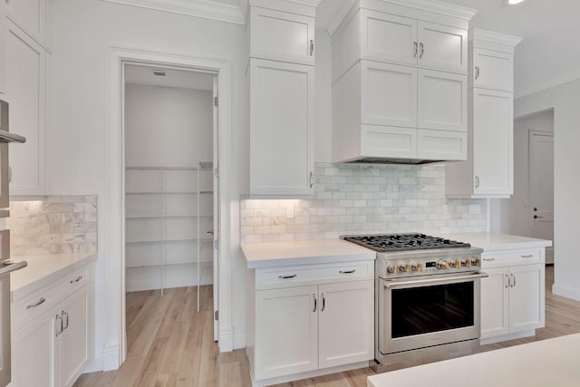 kitchen with white cabinetry, light countertops, light wood-style flooring, and high end stainless steel range