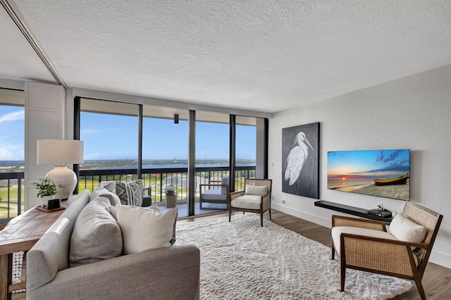 living room featuring hardwood / wood-style flooring, a wall of windows, and a textured ceiling