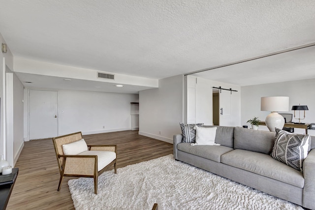 living room featuring wood-type flooring, a barn door, and a textured ceiling