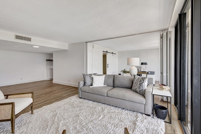 living room featuring a barn door, a textured ceiling, and light wood-type flooring