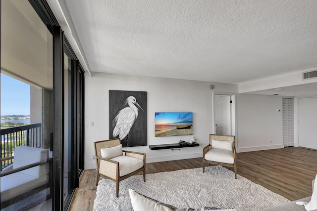 sitting room featuring light hardwood / wood-style floors, a water view, and a textured ceiling