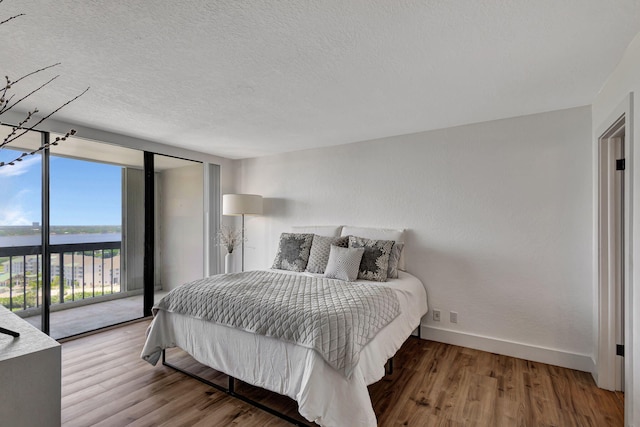 bedroom with access to exterior, hardwood / wood-style flooring, and floor to ceiling windows