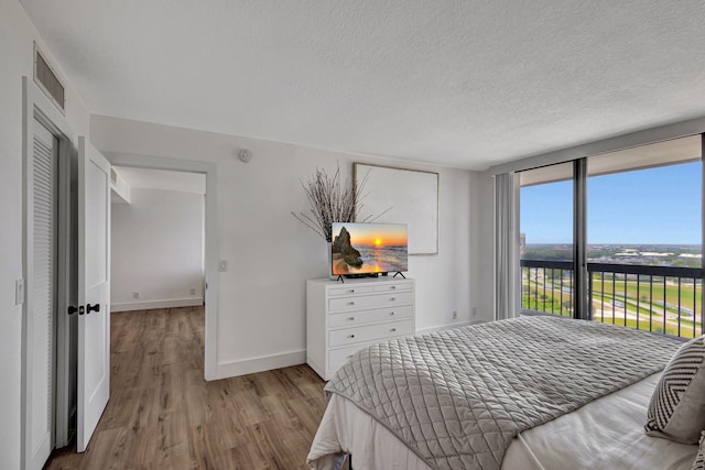 bedroom with a textured ceiling and light hardwood / wood-style flooring