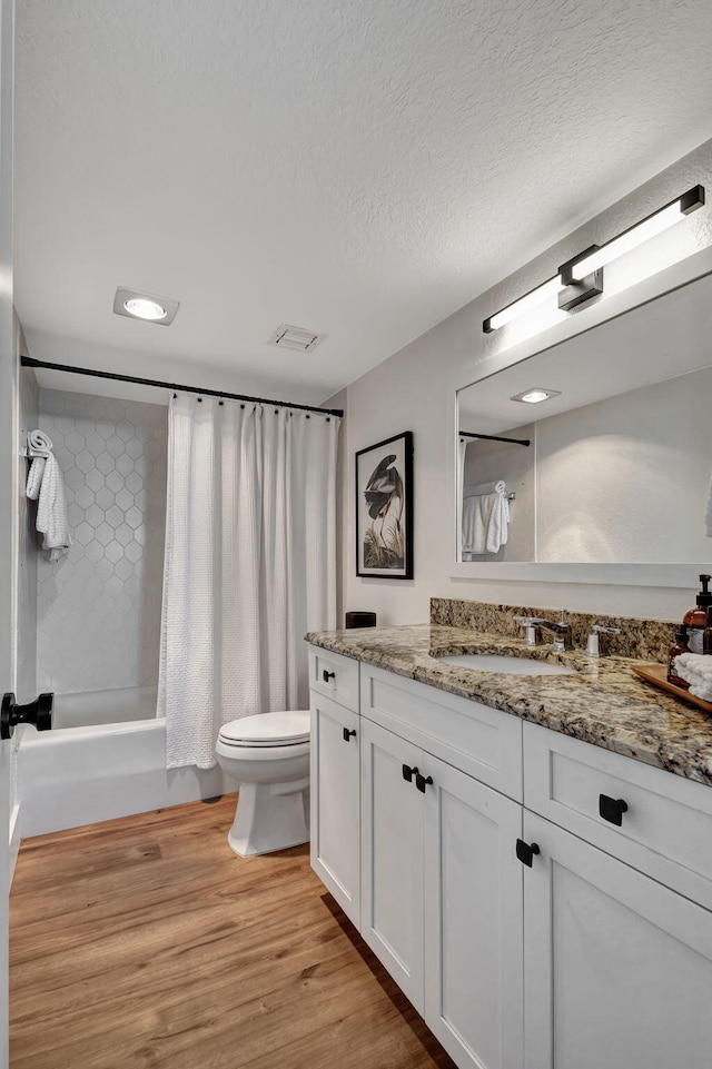 full bathroom with vanity, toilet, shower / bathtub combination with curtain, a textured ceiling, and wood-type flooring