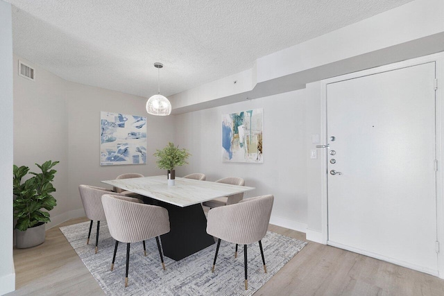 dining room featuring a textured ceiling and light wood-type flooring