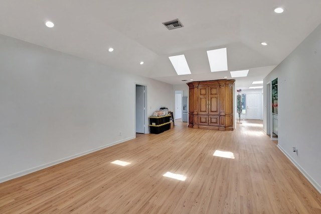 unfurnished living room with lofted ceiling with skylight and light wood-type flooring