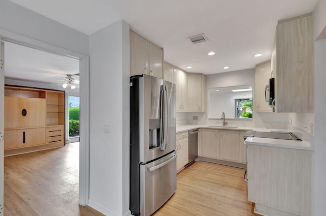 kitchen featuring stainless steel appliances, a healthy amount of sunlight, light brown cabinetry, and light wood-type flooring