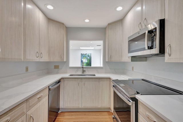 kitchen with sink, appliances with stainless steel finishes, light hardwood / wood-style flooring, and light brown cabinets