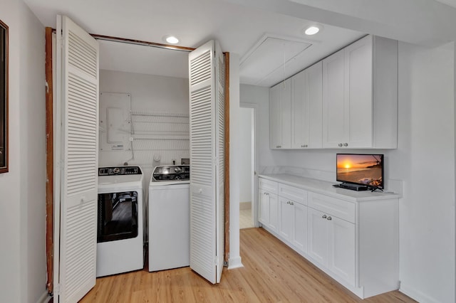 washroom with separate washer and dryer, light hardwood / wood-style floors, and electric panel