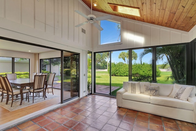 sunroom / solarium featuring wooden ceiling, lofted ceiling with skylight, ceiling fan, and plenty of natural light