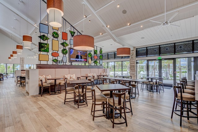 dining room featuring a healthy amount of sunlight, a towering ceiling, and light hardwood / wood-style flooring