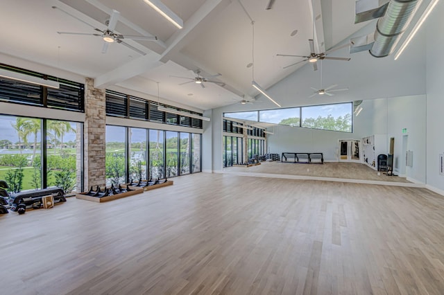 exercise room with light hardwood / wood-style floors, ceiling fan, and high vaulted ceiling