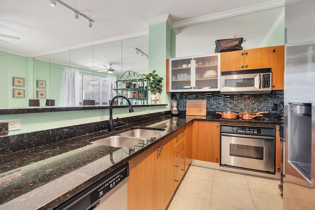 kitchen with sink, dark stone countertops, light tile patterned floors, ornamental molding, and appliances with stainless steel finishes