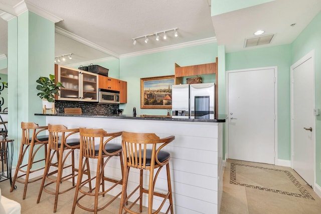 kitchen featuring kitchen peninsula, ornamental molding, a textured ceiling, stainless steel appliances, and light tile patterned floors