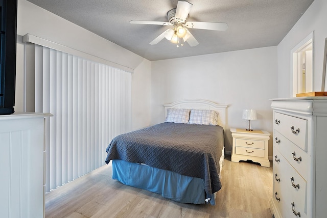 bedroom with ceiling fan, a textured ceiling, and wood finished floors