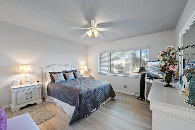 bedroom with a textured ceiling, ceiling fan, light wood finished floors, and baseboards