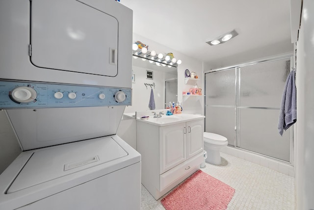 bathroom featuring stacked washer / dryer, toilet, vanity, and walk in shower