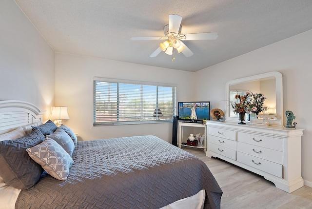 bedroom with a textured ceiling, light wood finished floors, and a ceiling fan