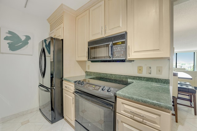 kitchen with light tile patterned flooring, cream cabinetry, and black appliances