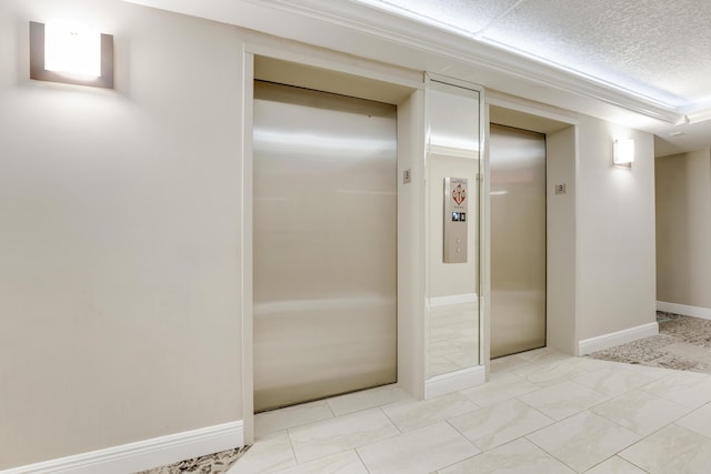 hall featuring a textured ceiling and elevator