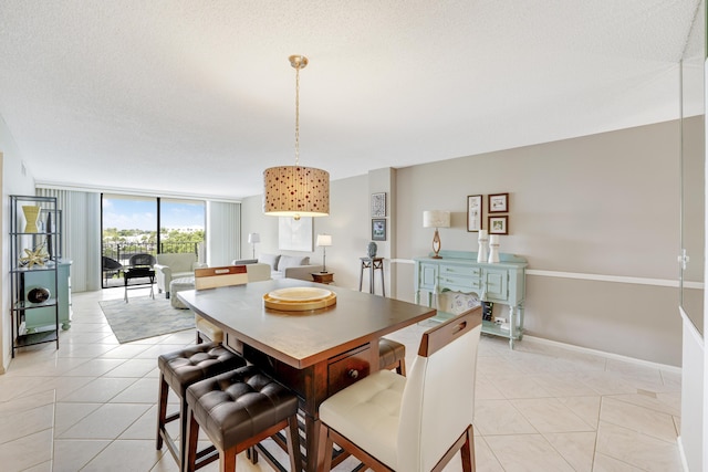 tiled dining room featuring floor to ceiling windows and a textured ceiling