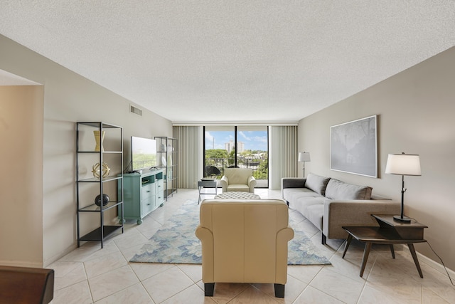 tiled living room featuring a textured ceiling and expansive windows