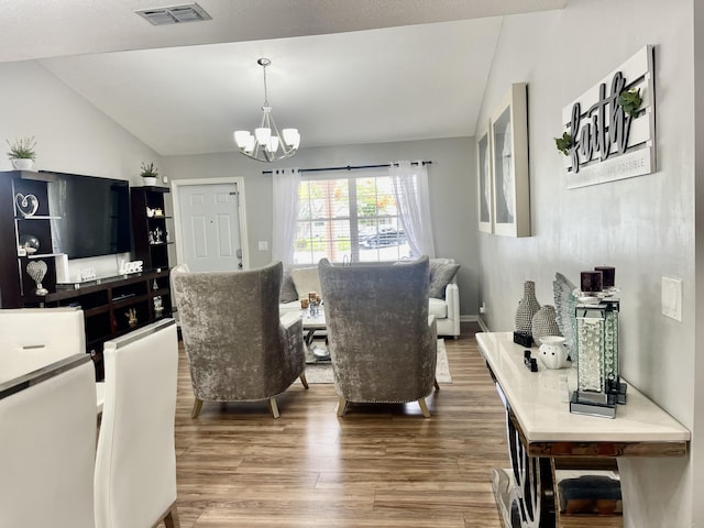 living room featuring hardwood / wood-style flooring, an inviting chandelier, and vaulted ceiling