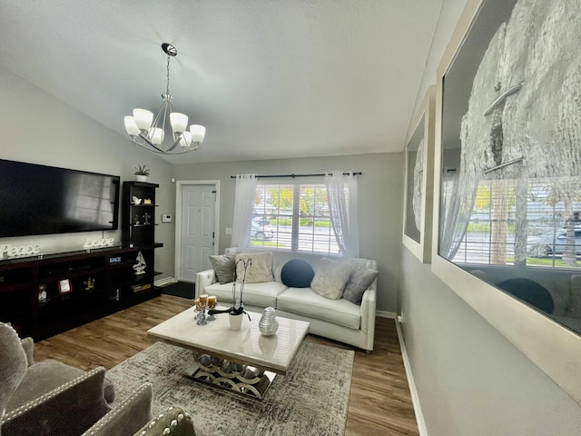 living room with hardwood / wood-style floors, vaulted ceiling, and an inviting chandelier