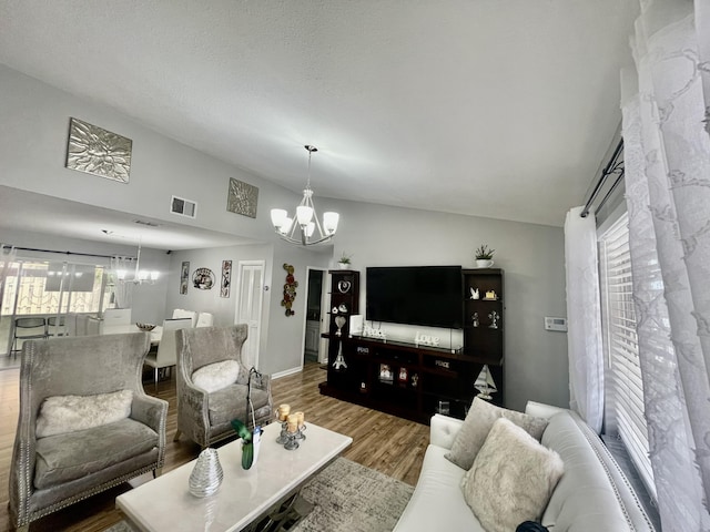 living room featuring hardwood / wood-style floors, vaulted ceiling, and an inviting chandelier