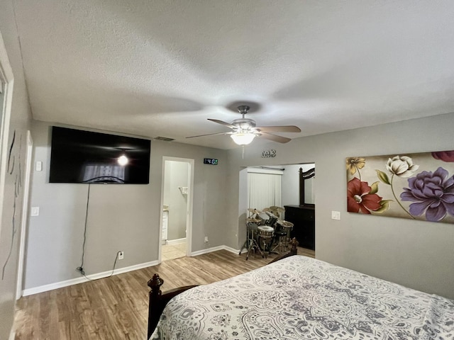 bedroom featuring ceiling fan, hardwood / wood-style floors, ensuite bathroom, and a textured ceiling