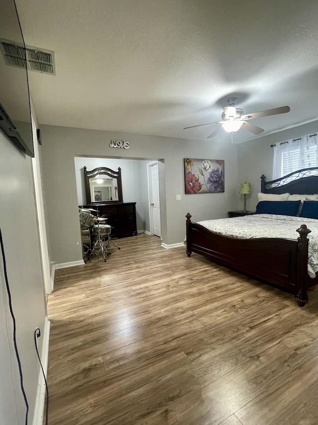 bedroom featuring ceiling fan, light hardwood / wood-style flooring, and a textured ceiling