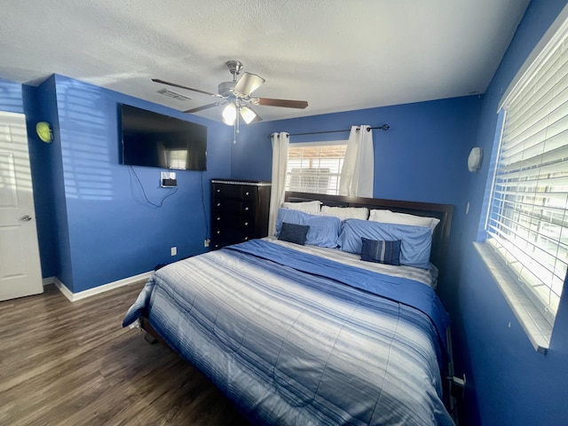 bedroom with hardwood / wood-style floors, ceiling fan, and a textured ceiling