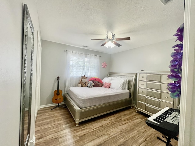 bedroom featuring ceiling fan, hardwood / wood-style floors, and a textured ceiling