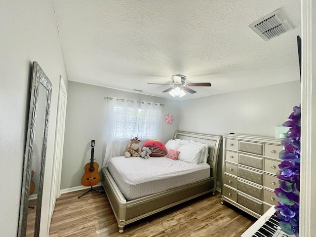 bedroom with hardwood / wood-style floors, ceiling fan, and a textured ceiling