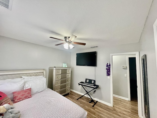 bedroom featuring hardwood / wood-style floors, a textured ceiling, and ceiling fan