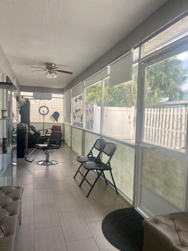 sunroom with a wall mounted air conditioner, ceiling fan, and a healthy amount of sunlight