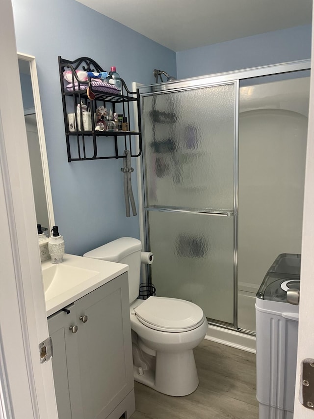 bathroom with toilet, vanity, a shower with door, and hardwood / wood-style flooring