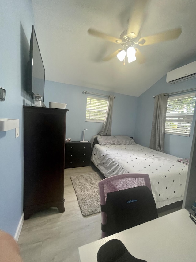 bedroom featuring ceiling fan, vaulted ceiling, light wood-type flooring, and a wall mounted AC