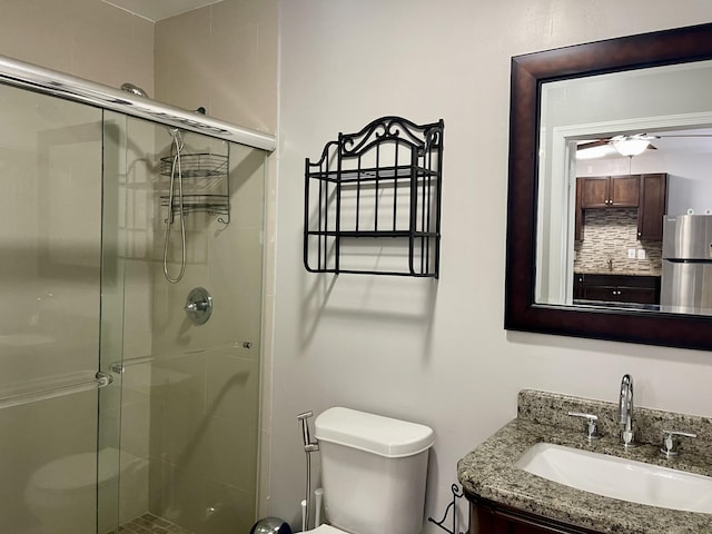 bathroom featuring vanity, toilet, an enclosed shower, and ceiling fan