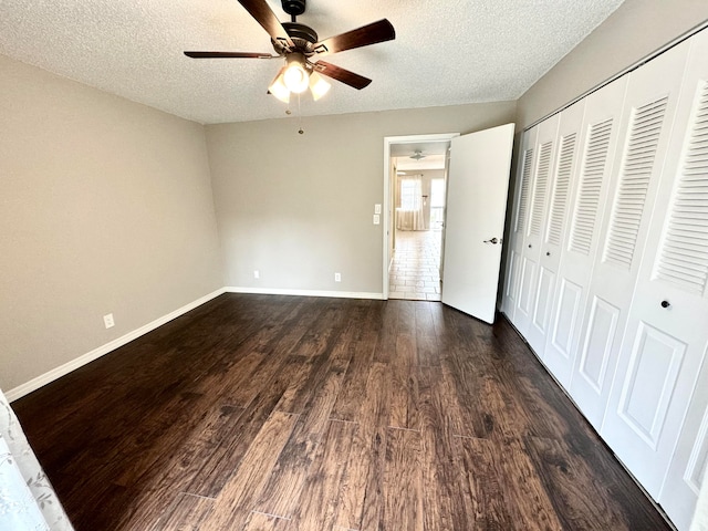 unfurnished bedroom with a closet, a textured ceiling, dark wood-type flooring, and ceiling fan