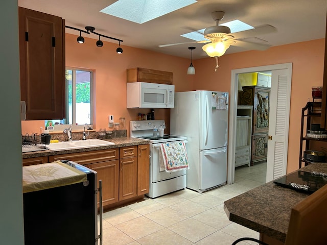 kitchen with a skylight, electric range, sink, fridge, and light tile patterned floors