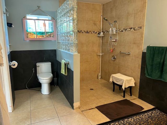 bathroom with tile patterned flooring, toilet, a tile shower, and tile walls