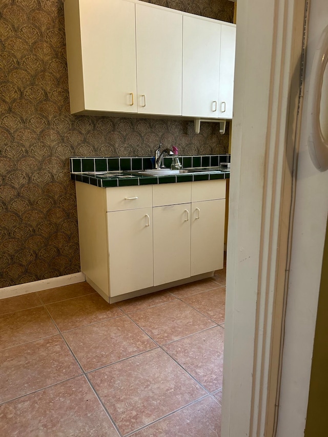 kitchen with tile counters, sink, light tile patterned floors, tasteful backsplash, and white cabinets