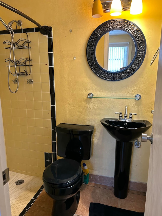 bathroom featuring tile patterned flooring, toilet, and tiled shower